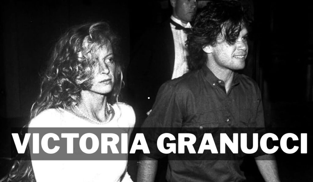 A black and white portrait of Victoria Granucci. She has long, dark, wavy hair and is looking directly at the camera with a slight, confident smile.